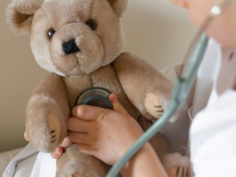 Ein Teddy der von einer Ärztin mit einem Stethoskop untersucht wird.